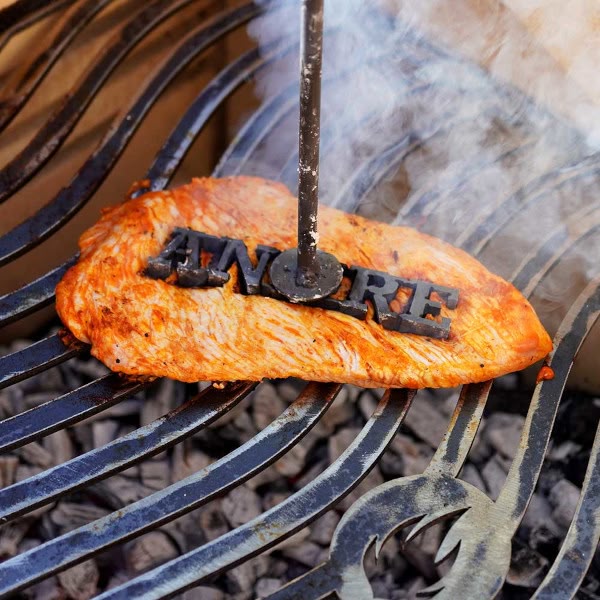 Heißer Grillstempel mit Name wird auf Steak gedrückt