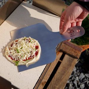 BlazeBox Pizzaschieber schiebt kleine Pizza auf Pizzastein