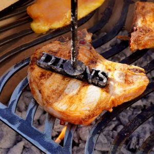 Heißer Grillstempel "DEINS" wird auf gegrilltes Steak gedrückt