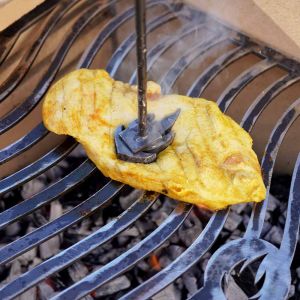 Grillstempel "Flamme" wird auf Hähnchensteak auf dem Grill gedrückt