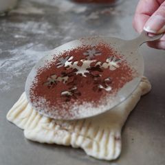 Motiv mit Brot- und Kakaoschablone Schneekristall aus Edelstahl auf Gebäck gestalten