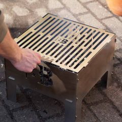 Mit Grillrostgabel den Grillrost in die BlazeBox Cube Medium setzen
