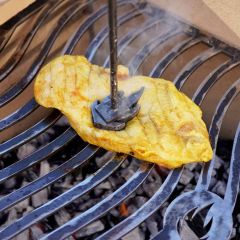 Grillstempel "Flamme" wird auf Hähnchensteak auf dem Grill gedrückt