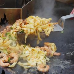 Mit dem Grillwender aus hochwertigem Edelstahl asiatische Bratnudeln mit Garnelen von der Grillplatte nehmen