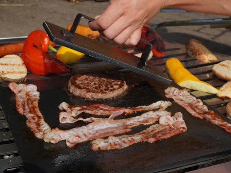 Fleischbeschwerer von saftig gegrilltem Patty auf Grillrost nehmen