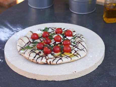 Pizza Tomate-Basilico liegt auf Pizzastein aus Keramik