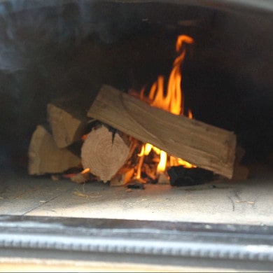 Pizzaofen anfeuern - Holzscheite nachlegen