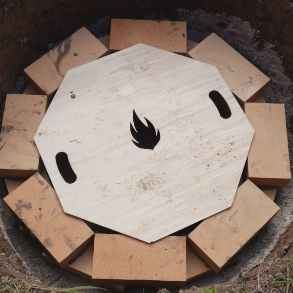 Schablone liegt auf fertigen zweiten Reihe der Feuerstelle im Garten