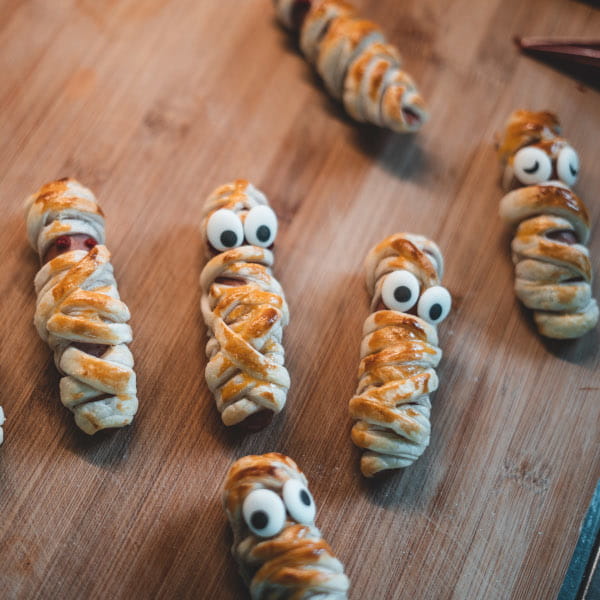 Gebackene Blätterteig-Mumien mit Würstchen mit aufgeklebten Zuckeraugen