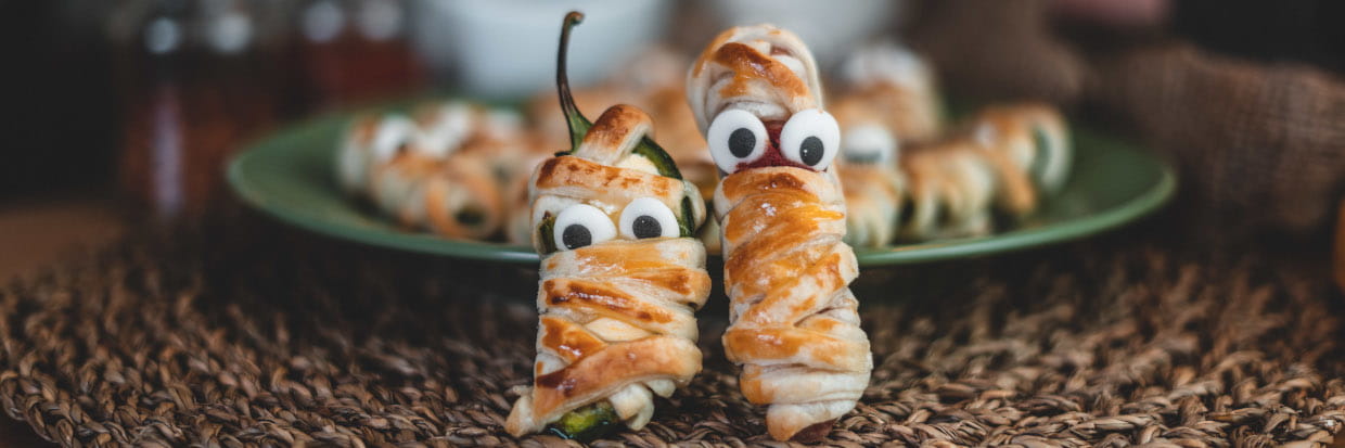 Blätterteigmumien vor einem Teller aufgestellt