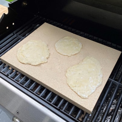 Naan Brot auf dem Pizzastein für den Grill backen