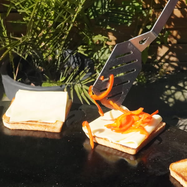 Toasts mit geschmolzenem Käse und Paprikastreifen auf Feuerplatte