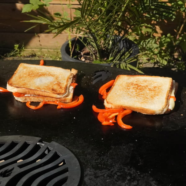 Belegte Käse Sandwiches grillen auf der Feuerplatte