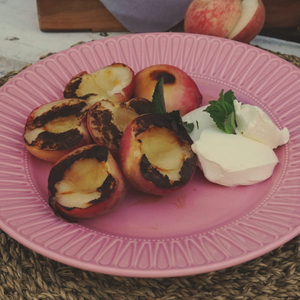 Flambierte Pfirsische mit Eis und Minzblättern auf Teller