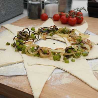 Teig-Stern mit gegrillten Zwiebeln und Paprika belegt