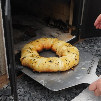Cheese Steak Ring mit Pizzaschieber aus dem Pizzaofen holen