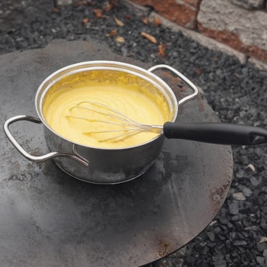 Topf mit Käsesauce auf Feuerplatte