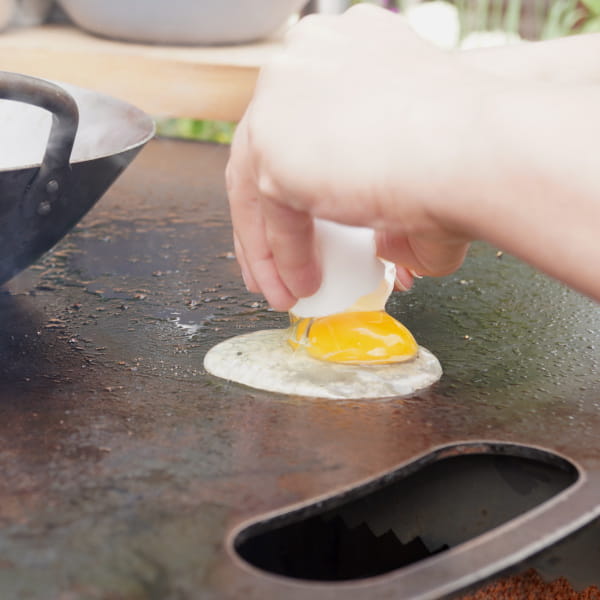 Ei auf der Feuerplatte aufschlagen und braten