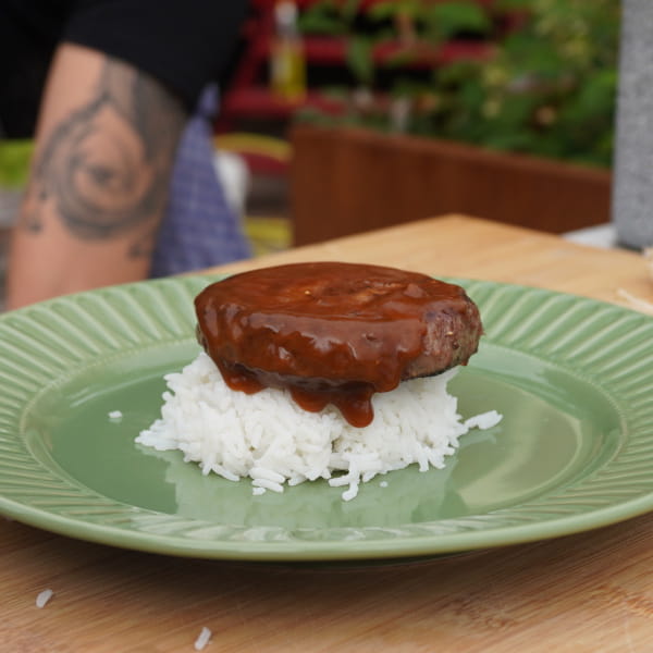 Teller mit Reis, Burgerpatty und Soße darauf