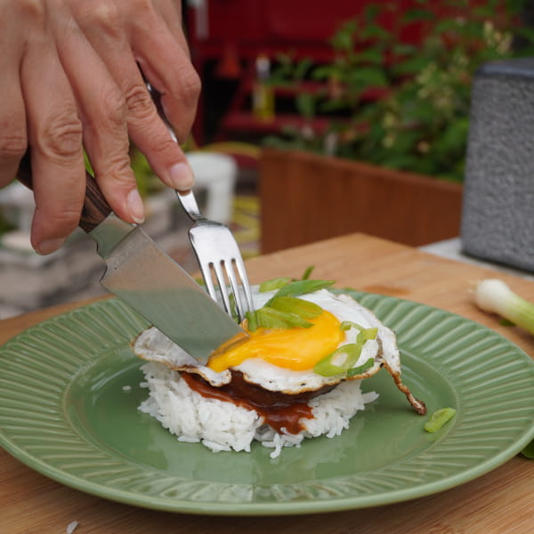 Reis geschichtet mit Burger Patty, Soße und Ei aufschneiden