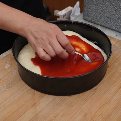 Tomatensauce auf Pizzaboden verteilen