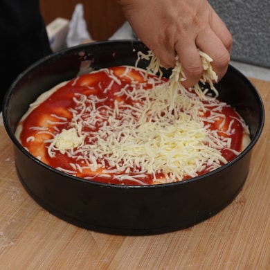 Pizza mit Käse bestreuen