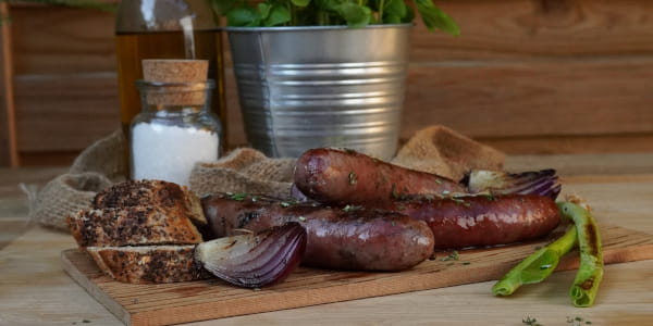Wildwürstchen rustikal angerichtet mit Zwiebeln und Brot
