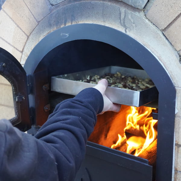 Bakblech mit den eingelegten Nüssen im Pizzaofen backen